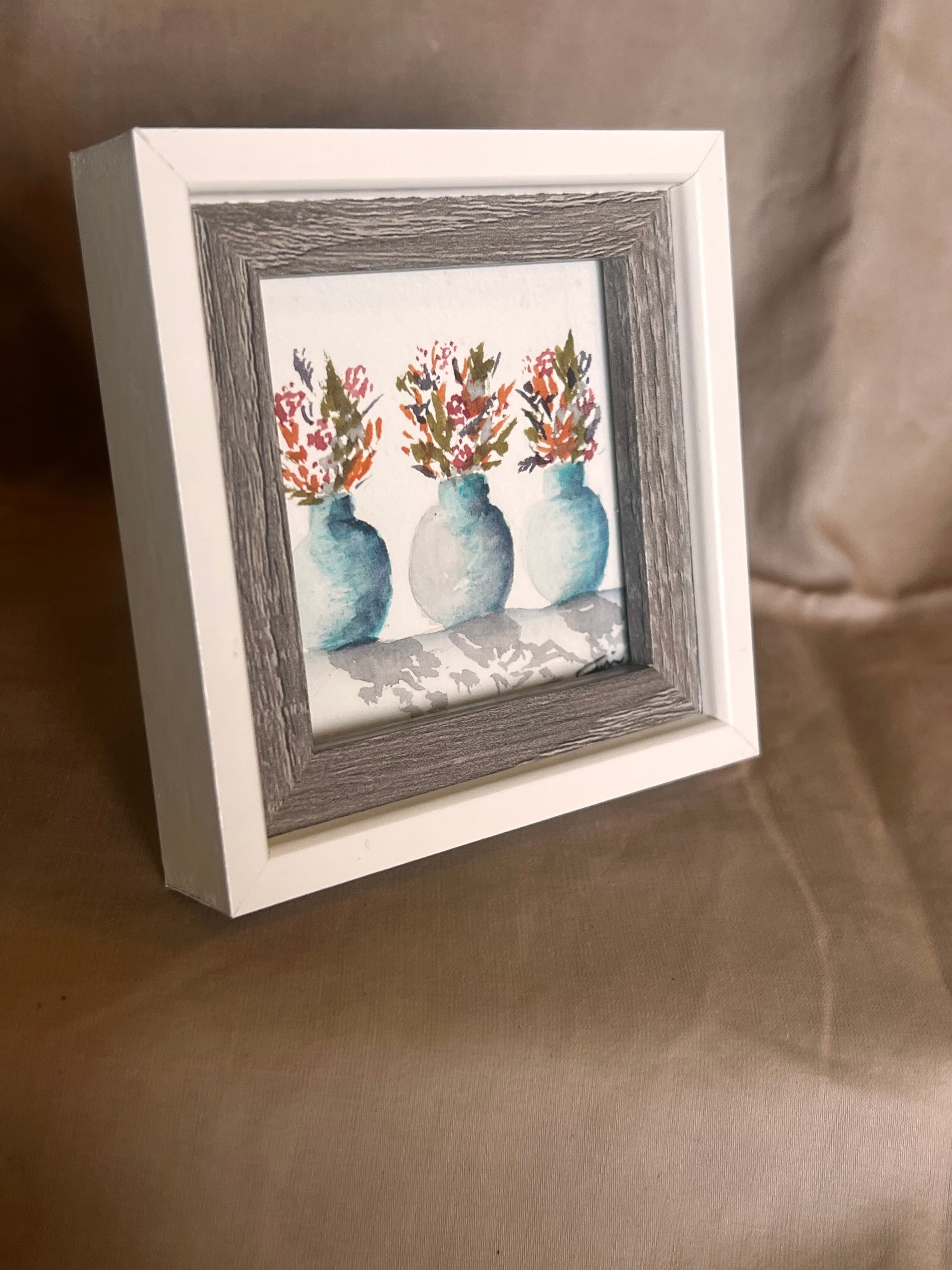 Framed artwork with a floral design in a white and wooden style frame