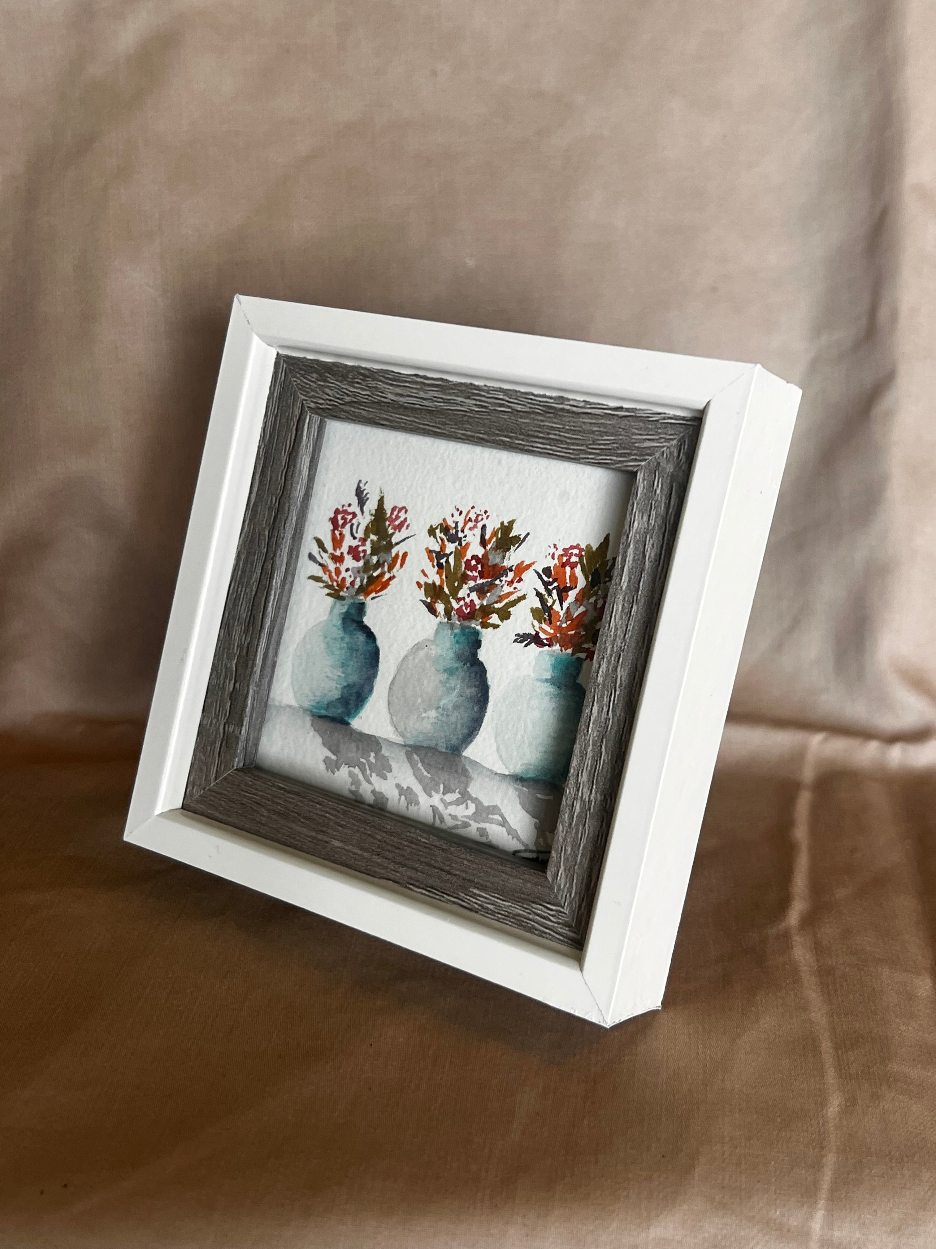 Small framed artwork with floral design on a textured surface